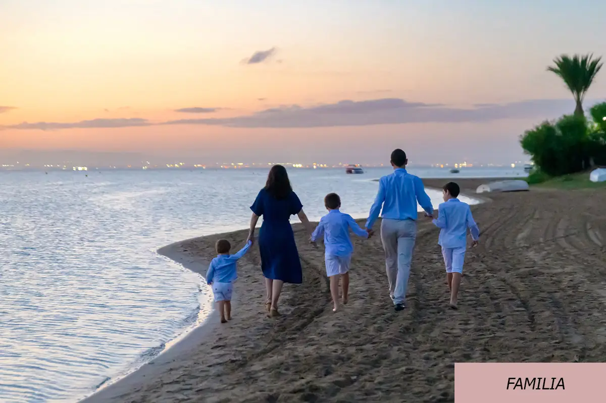 Imagen de una familia con tres niños paseando de la mano por la orilla de la playa